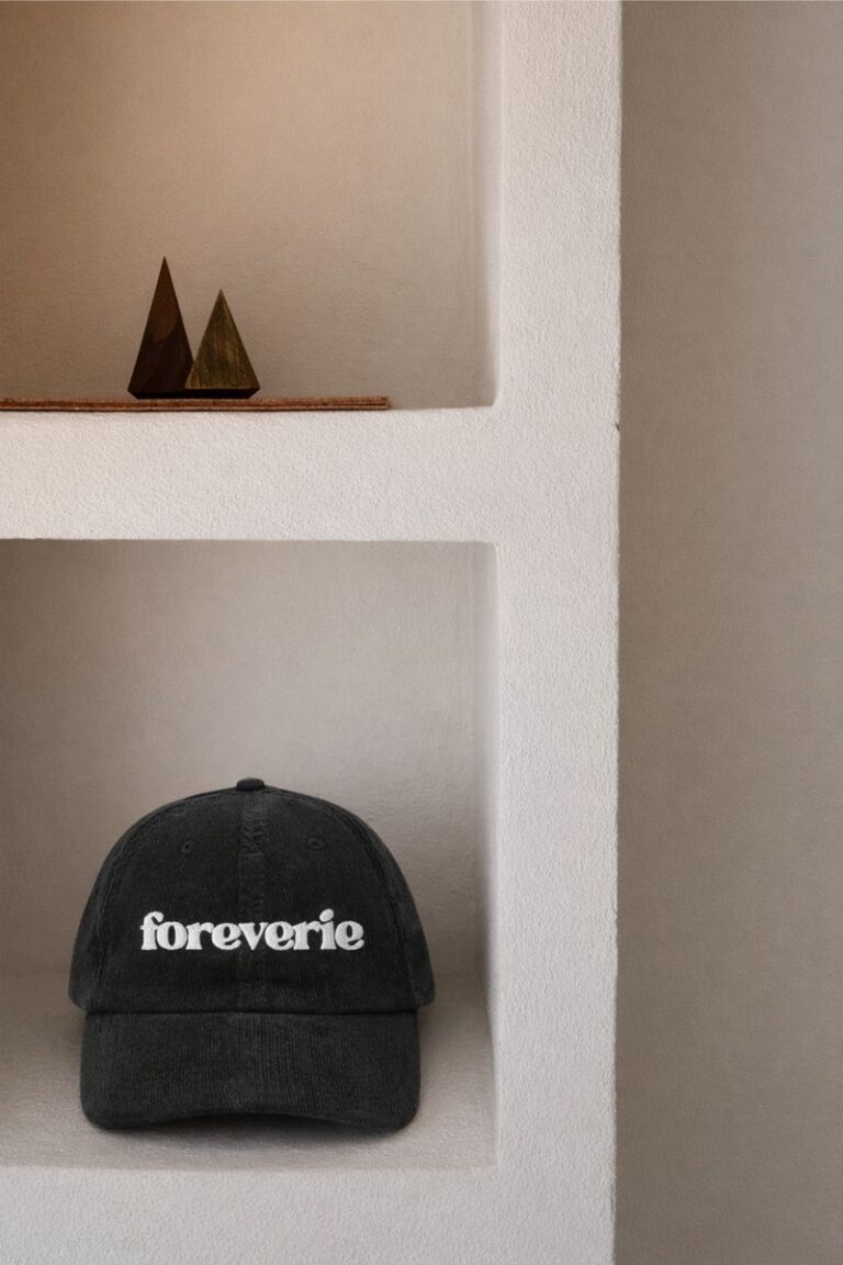 Black Foreverie corduroy cap displayed on a white built-in shelf with minimalist decor