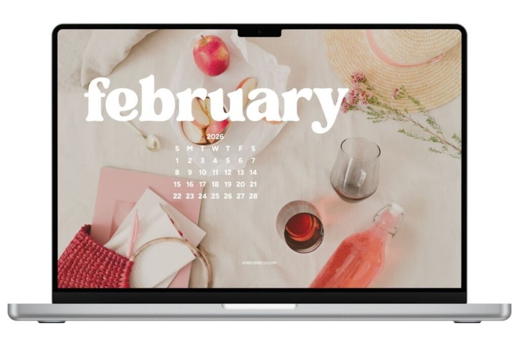 Laptop mockup displaying February 2026 desktop wallpaper with soft pink picnic aesthetic and minimal calendar overlay.