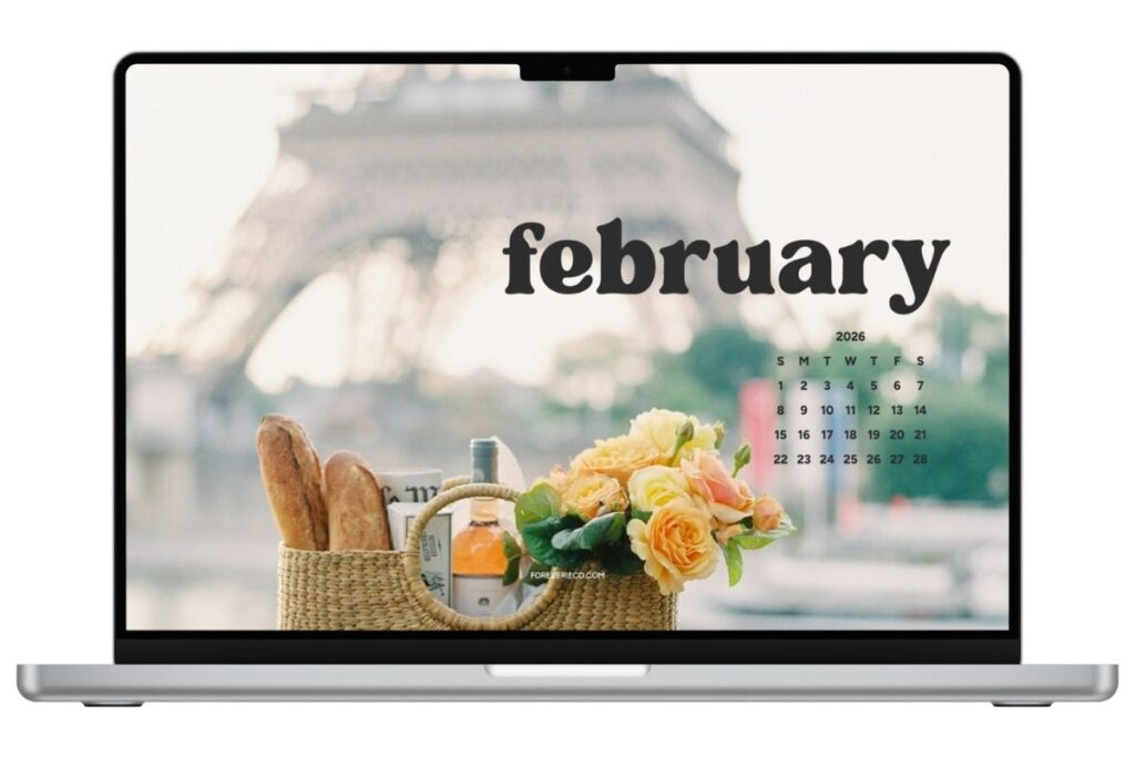 Laptop mockup displaying February 2026 Paris desktop wallpaper with Eiffel Tower and floral arrangement.