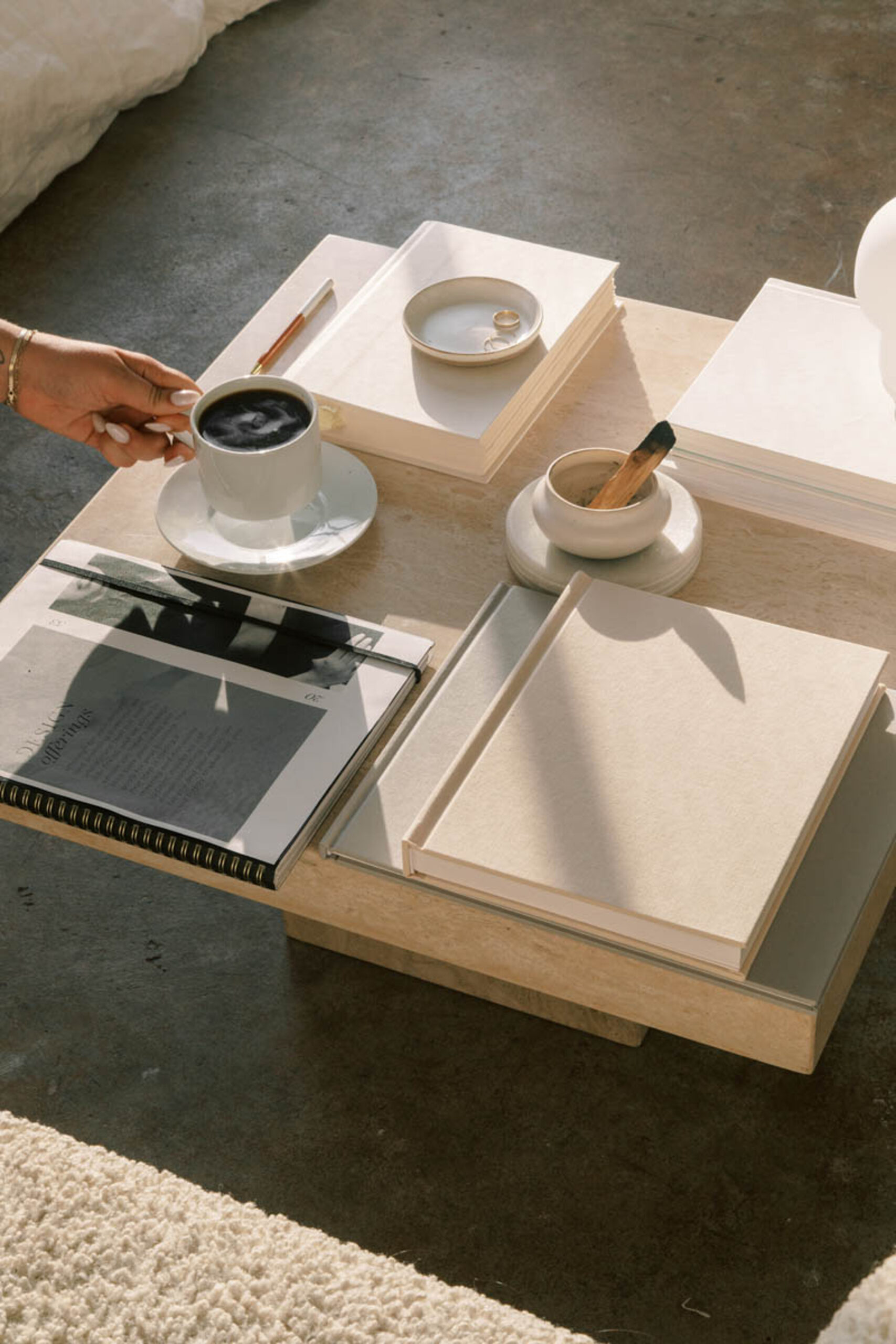 Minimal table with coffee cup, stacked books, and neutral decor in warm natural light