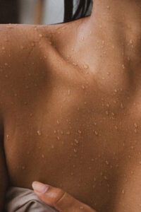 Close-up of glowing skin with water droplets on the chest and shoulder after a shower.