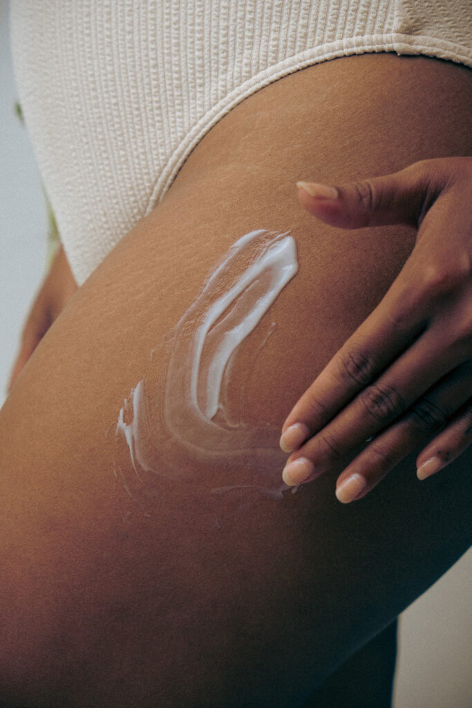 Applying moisturizing body cream as part of a quiet luxury beauty routine.
