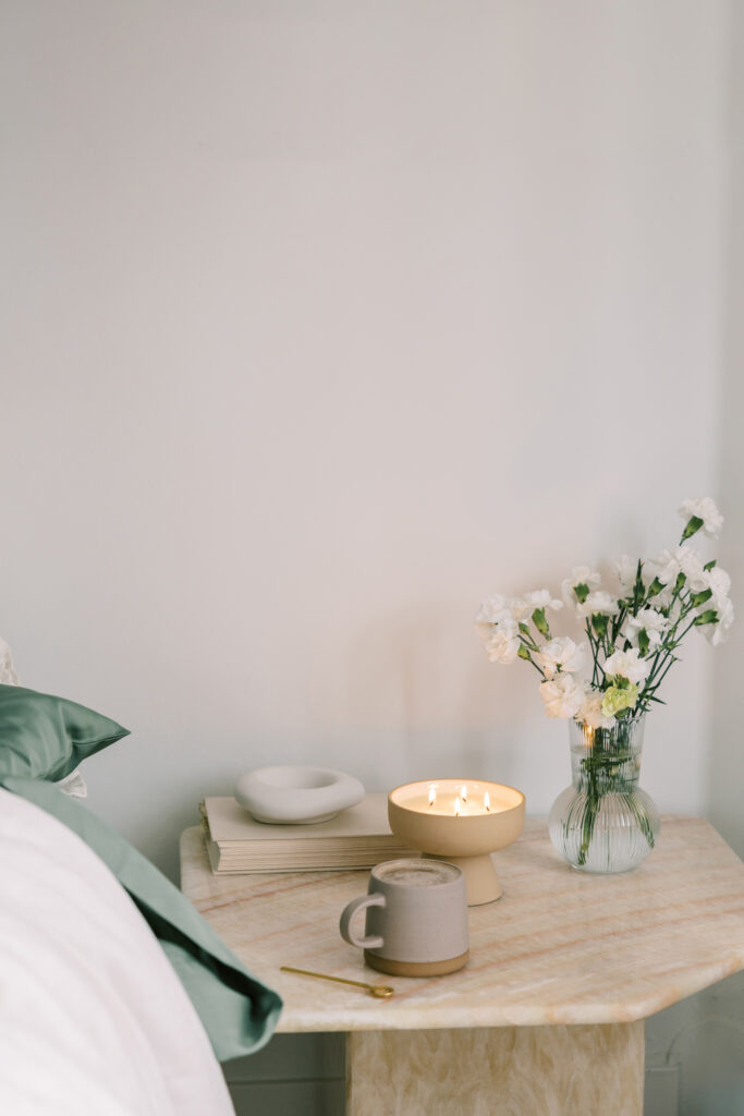Minimal bedside table with flowers, candle, books, and tea