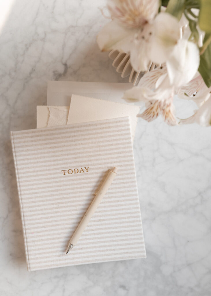Minimal journal with pen and handmade paper on a marble countertop