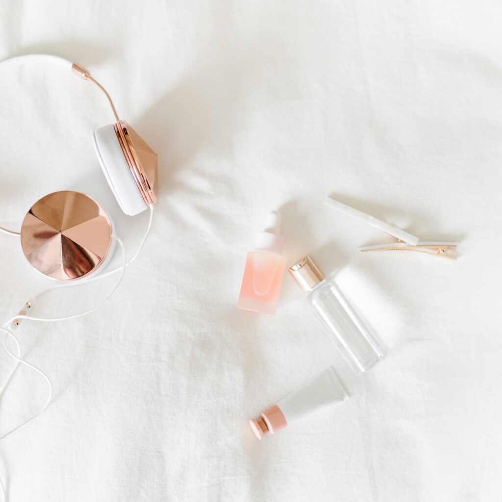Minimal beauty products and skincare arranged on a white bed