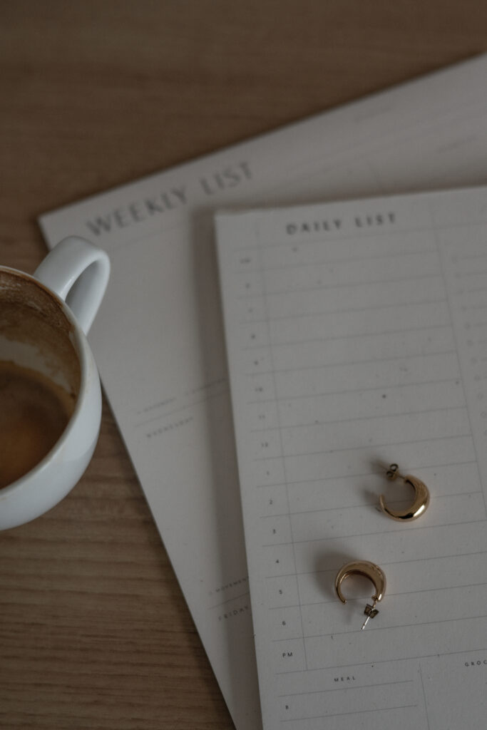 Weekly planner beside coffee and gold hoop earrings